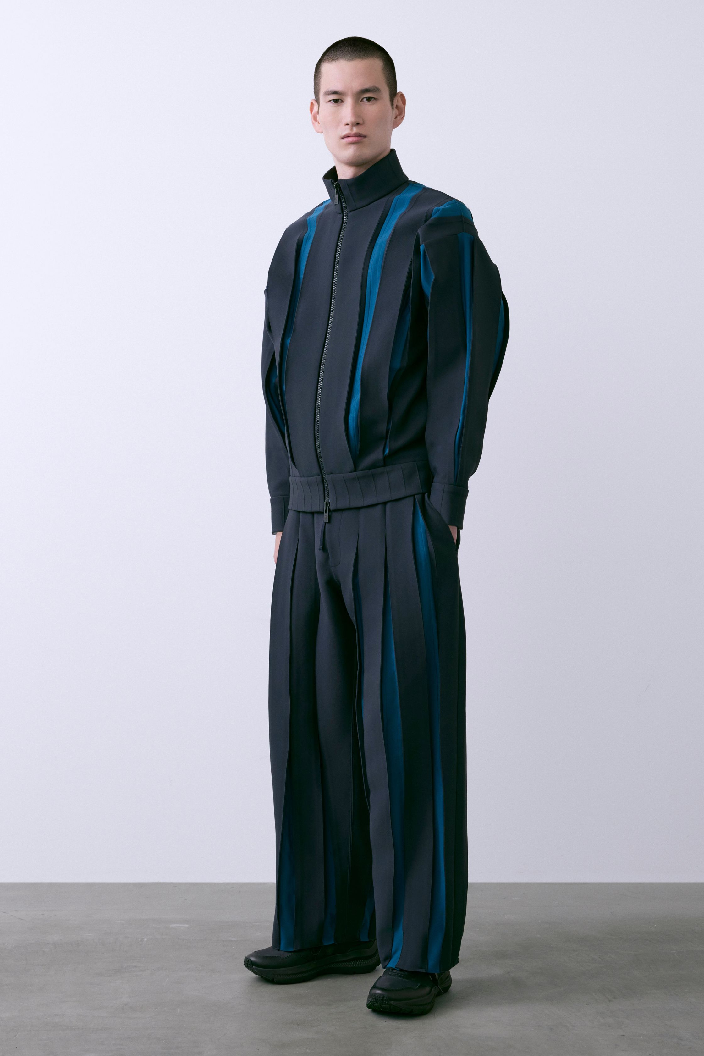 CFCL 26FW 以计算机针织为核心语言，将服装转化为可被“阅读”的结构体。纵向纹理、立体褶皱与模块化比例在黑、深蓝与青绿色中展现理性秩序，既冷静又富有身体律动。系列强调零浪费与可持续逻辑，在极简外观下隐藏高度技术复杂性，构建一种介于未来制服与当代艺术之间的男装形态，是日本新世代设计中最具系统美感的表达之一-顽石频道趋势研究